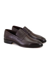 Bruine leren loafers met een zachte afwerking, voorzien van een lage hak en een gestikte naad over de wreef. Elegant ontwerp met een scherpe neus.