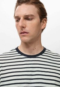 Striped T-shirt made of light fabric featuring horizontal black and cream stripes, with a round navy neckline and short sleeves.