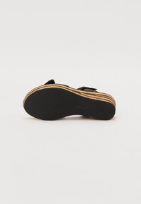 Sorte sandaler med en teksturert gummisåle og lagdelt treplattform; har en justerbar stropp og en glatt fotseng for komfort.