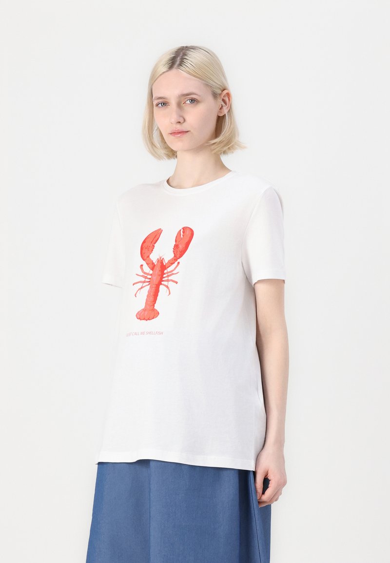 Camiseta de algodón blanca con un gráfico de una langosta roja y el texto "Solo llámame egoísta." Mangas cortas y corte holgado. Fondo liso.
