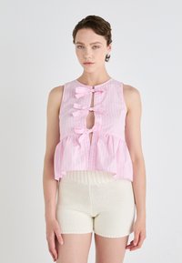 Top senza maniche a righe rosa e bianche con design a peplum, caratterizzato da tre fiocchi decorativi e un'apertura a chiave frontale.