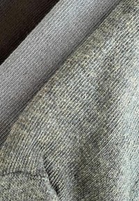 Drei Stoffstücke in Grau, Oliv und Dunkelbraun mit sichtbaren Webmustern, unterschiedlichen Dicken und sichtbaren Nähten.