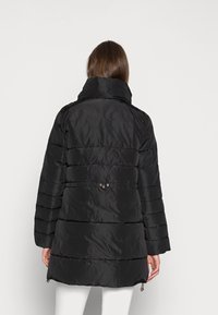 Schwarze Daunenjacke mit hohem Kragen, mit gesteppten Abschnitten, tailliert mit Hardware-Details und seitlichen Reißverschlüssen. Glatte, glänzende Textur.