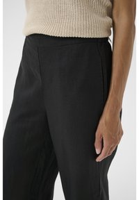 Zwarte linnen broek met een ontspannen pasvorm, met een gladde textuur en zijzakken, gecombineerd met een lichtbeige gebreid topje.