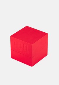 Rote strukturierte Box mit eingeprägtem "DIESEL"-Logo. Quadratische Form, glatte Oberfläche und ein Deckel, der sicher sitzt. Keine zusätzlichen Verzierungen.