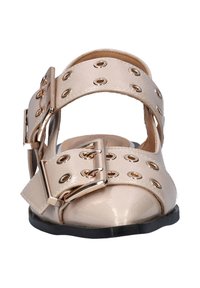 Beige gepatineerde leren sandalen met meerdere uitsparingen, gouden oogjes en grote decoratieve gespen. Vlakke zwarte zool met een ronde neus.