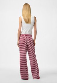 Sarkani un balti svītraini platajiem biksēm, kas piedāvā brīvu piegriezumu un elastīgu jostu. Gluda tekstūra ar ribotu dizainu.