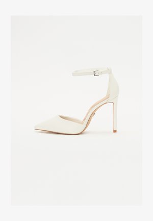 White leather high-heeled shoe with a pointed toe and thin ankle strap. Features a stiletto heel and minimalistic design.