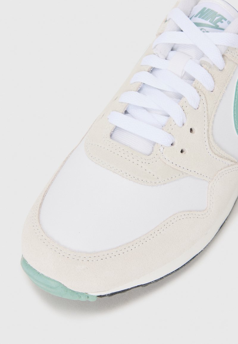 White sneaker with suede and mesh materials, featuring a mint green accent, round toe, and white laces. Light neutral colorway.