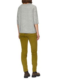 Helles graues Strickpullover mit Dreiviertelärmeln, kombiniert mit olivgrünen Cordhosen und schokoladenbraunen Stiefeletten.
