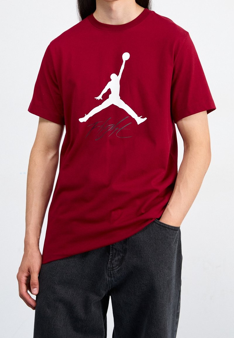 Bordowa bawełniana koszulka z krótkim rękawem, z dużym białym logo Jumpman i graficznym napisem "Flight" w kolorze srebrnym. Okrągły dekolt.