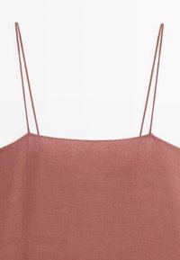 Mouwloze jurk of top met vierkante halslijn in stoffig roze linnen stof met dunne dubbele spaghettibandjes op een witte achtergrond.