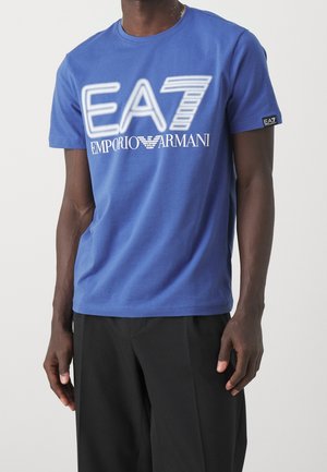 Camiseta de algodón azul con un atrevido logo de EA7 en blanco y azul claro en la parte delantera, de manga corta y diseño de cuello redondo.