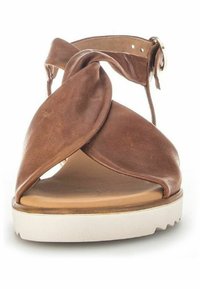 Bruine leren sandal met gedraaide banden, verstelbare enkelgesp en een witte plateauzool met textuurdetails.