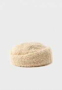 Beige, runder Hut aus einem weichen, strukturierten Fleece-Material mit einem glatten, gerafften Band um die Unterseite.