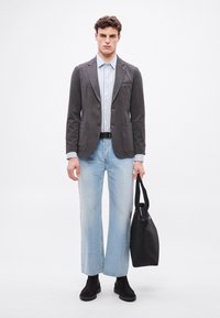 Γκρι σακάκι με δύο εμπρόσθιες τσέπες, ανοιχτό μπλε ριγέ πουκάμισο, φαρδιά ανοιχτό τζιν παντελόνια, μαύρη ζώνη, μαύρη τσάντα και μαύρα μποτάκια μέχρι τον αστράγαλο.