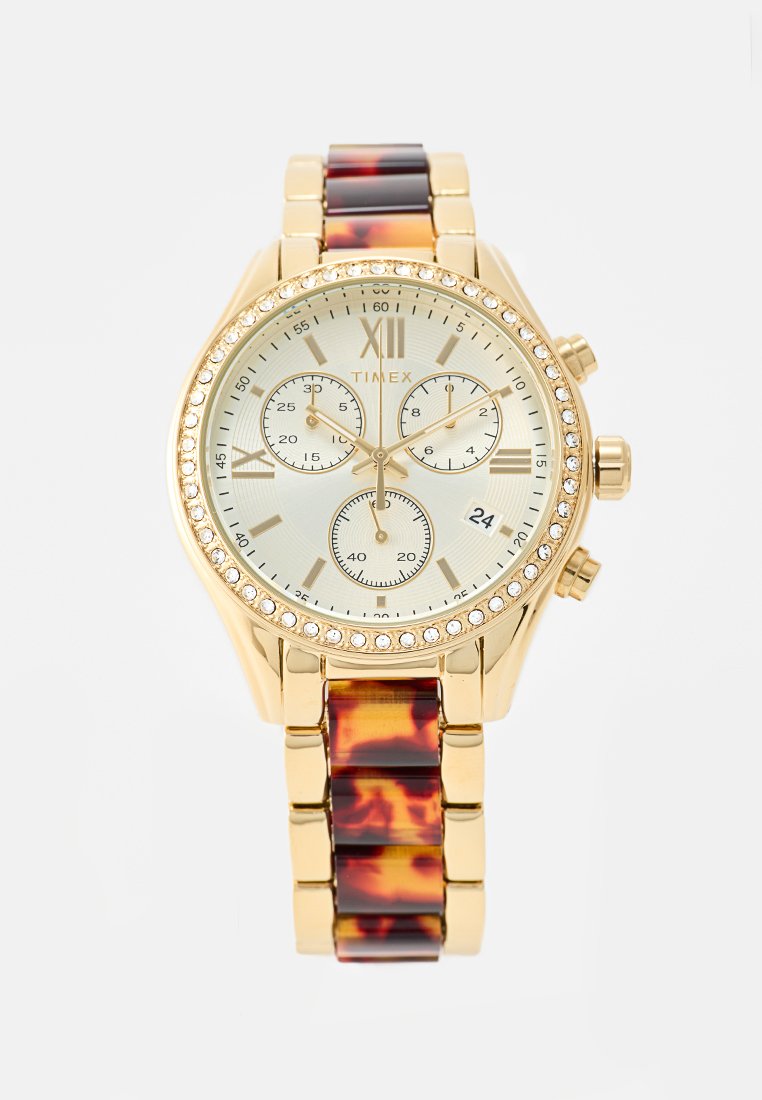 Reloj cronógrafo dorado con una esfera crema, números romanos, tres subesferas y una pulsera con patrón de carey. El bisel está adornado con piedras de imitación.