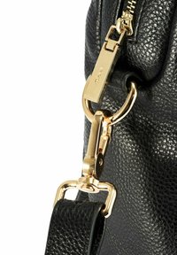 Czarna torba z fakturowanej skóry z złotym suwakiem i zapięciem łączącym czarny skórzany pasek z złotym pierścieniem.