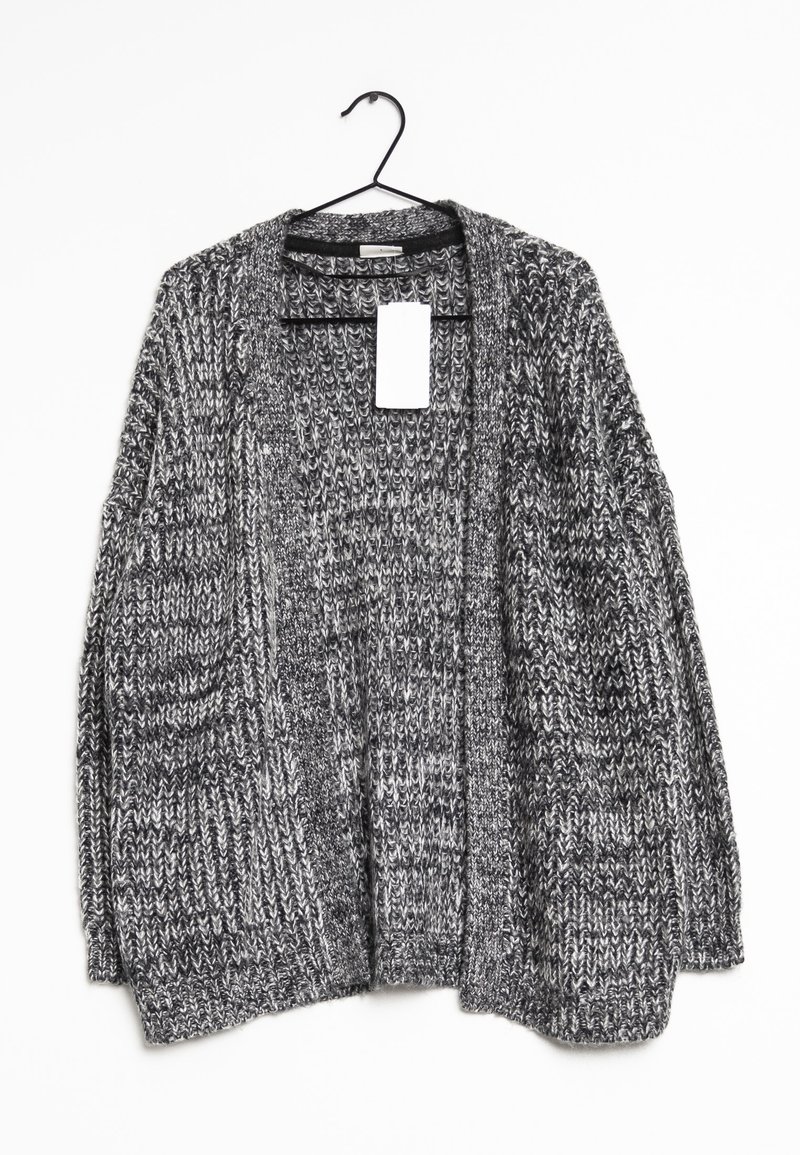 Grå stickad cardigan som hänger från en svart krok, med lös passform, öppen front och en tagg fäst vid kragen.