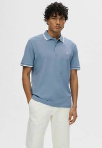 Polo shirt azzurro chiaro in cotone, con accenti a strisce bianche sul colletto e sulle maniche, caratterizzato da una patta con bottoni e dettaglio del logo.