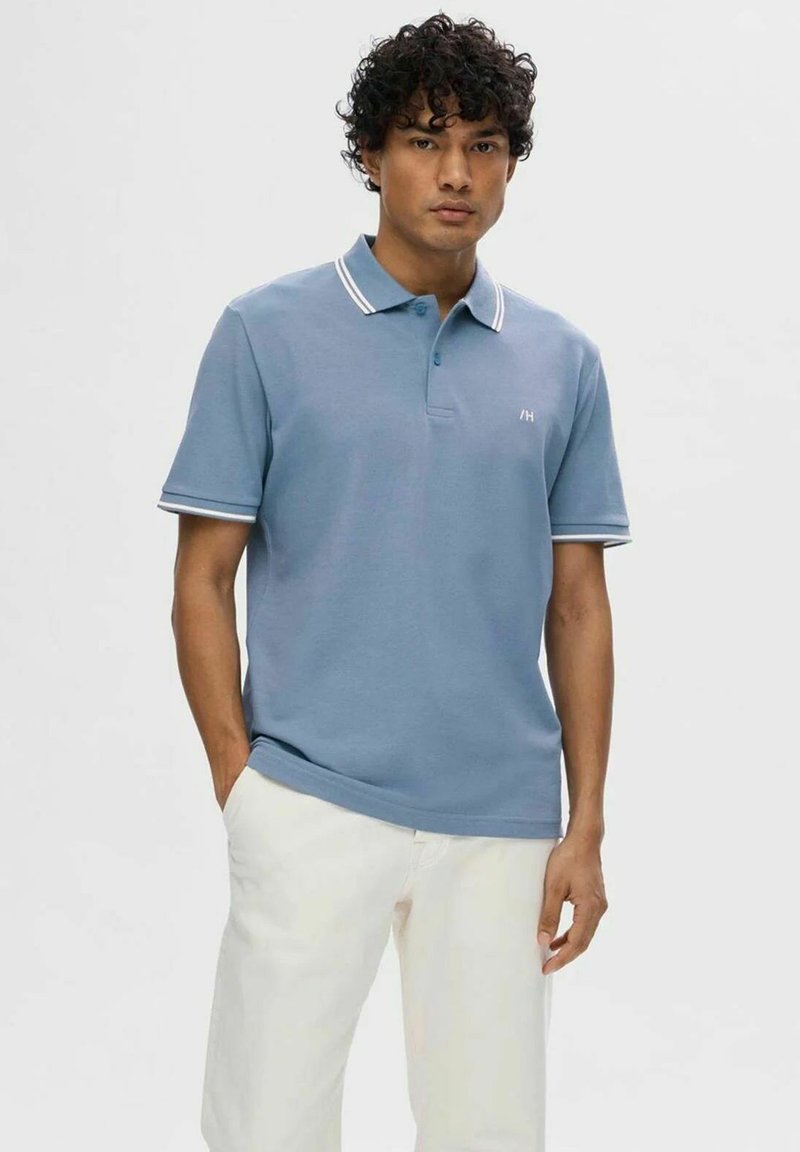 Polo shirt azzurro chiaro in cotone, con accenti a strisce bianche sul colletto e sulle maniche, caratterizzato da una patta con bottoni e dettaglio del logo.