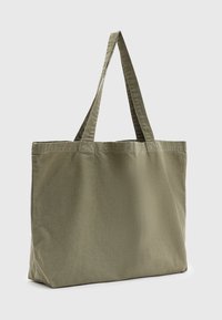 Borsa tote in tela verde oliva con due manici, forma rettangolare e una texture morbida. Design minimalista senza accenti aggiuntivi.