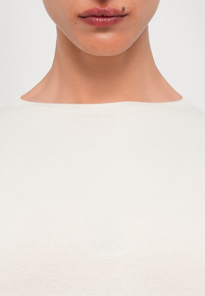 Light beige ribbed fabric with a rounded neckline, close-fitting design, and smooth texture, showcasing minimal stitching details.