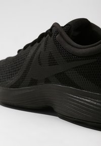 Musta urheilusandaali, jossa on teksturoitu verkkomateriaali yläosassa, pehmustettu nilkkapanta ja kaareva kevyt pohja. Sivussa on sävyvirheinen swoosh-logo.