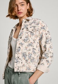 Blomstermønstret denimjakke i lys beige med flerfargede design. Har tradisjonell krage og frontknapper, og er utstyrt med to brystlommer.