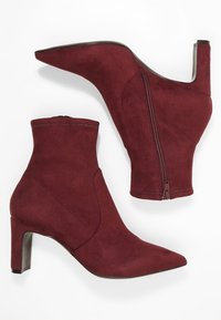 Burgundské semišové kotníkové boty s špičatou špičkou, bočním zipem a blokovým podpatkem vysokým 10 cm. Hladká textura s přiléhavým střihem.