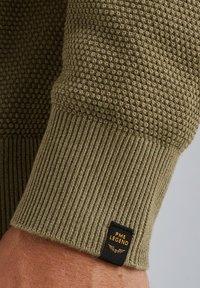 Olivgrüner Strickpullover mit strukturiertem Muster, gerippten Bündchen und schwarzem Etikett mit der Aufschrift "PME LEGEND". Weicher, dicker Stoff.