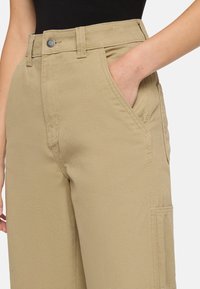 Beige katoenen broek met een rechte snit, zijzakken en een voorclosure met een knop en zichtbare stikdetails.