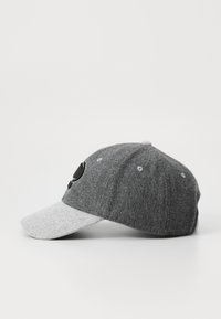 Grå kasket med en m�ørkere grå krop og lys grå skygge. Har et broderet design foran og seks ventilationshuller på toppen.