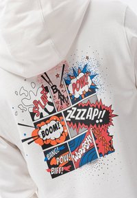 Felpa bianca con una grafica in stile fumetto. Presenta testi colorati come "SPLAT", "BOOM" e "POW!" su sfondi a motivi vari.