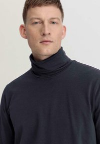 Dunkelgrauer Rollkragenpullover aus weichem Stoff, mit einer taillierten Passform, hohem Kragen und langen Ärmeln auf einem neutralen Hintergrund.