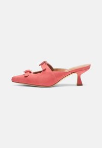 Slingback muil in koraal sued met puntige teen, twee kleine strikjes aan de voorkant en een mid-hoge, gebogen hak. Zachte textuur.