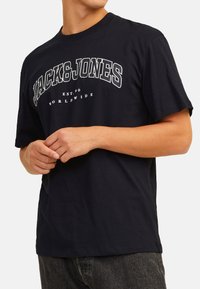 Dunkelblaues T-Shirt mit kurzen Ärmeln aus Baumwolle. Mit dem weißen "JACK&JONES"-Logo, darunter "EST. 90" und "WORLDWIDE" aufgedruckt.