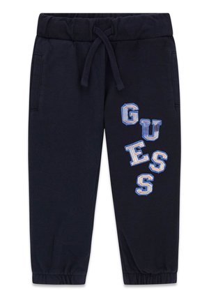Pantaloni sportivi blu navy con vita e polsini elasticizzati, tasche frontali e scritta "GUESS" in blu e bianco sulla gamba destra.