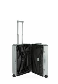 Valise rigide argentée avec poignée télescopique, quatre roues, intérieur noir, poches en mesh et ceintures pour sécuriser le contenu.