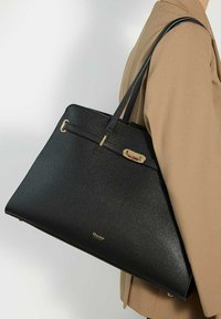 Black leather tote bag with a structured shape, long handles, and gold hardware accents. Smooth texture, featuring a logo on the front.
