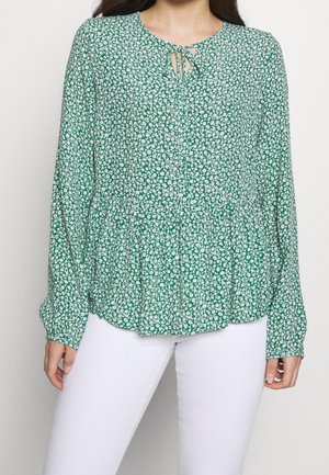 Blusa floreale verde con maniche lunghe, vita arricciata e dettaglio a chiave sul collo. Realizzata in tessuto leggero con piccoli fiori bianchi.