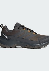 Sort og grå trail løbesko med en robust, tekstureret Overdel, kontrasterende brune accenter og en slidstærk ydersål til godt greb.