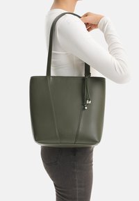 Olive green tote bag made of smooth synthetic material, featuring a minimalist design with two sturdy handles and decorative tassels.