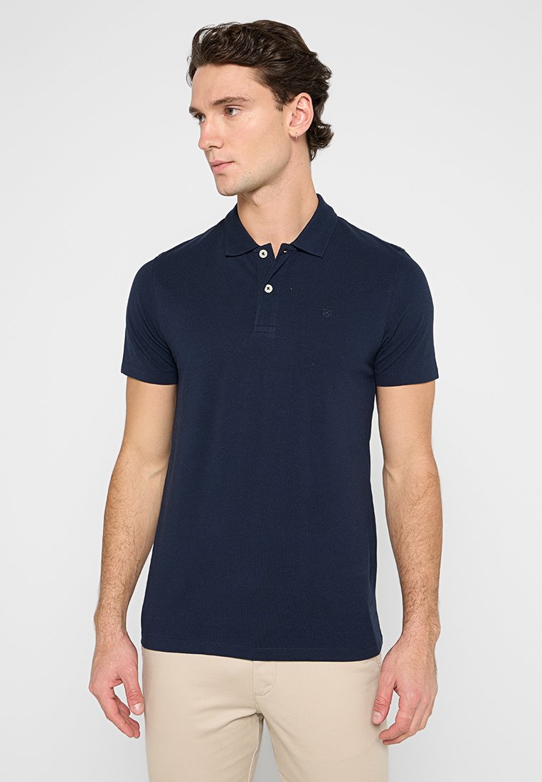 Mornarska polo majica s kratkimi rokavi, s plaketko na tri gumbe in diskretno vezenim logotipom. Gladek bombažni material z oprijetim dizajnom.
