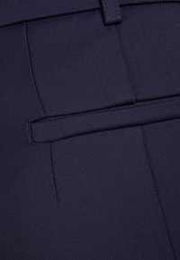 Pantalones azul marino ajustados, elaborados con una tela suave que presenta un frente liso con un bolsillo y detalles de costura precisos.