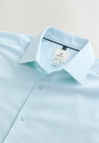 Lichtblauw, regular fit shirt met een puntige kraag, knoopsluiting en een gladde textuur. Label zichtbaar met merknamen en maatdetails.