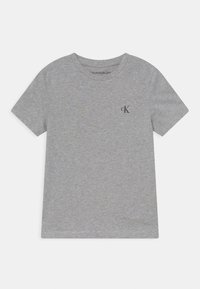 Tricou din bumbac gri, cu guler rotund și mâneci scurte. Are un mic logo negru "ck" pe partea stângă a pieptului. Textură moale, design casual.