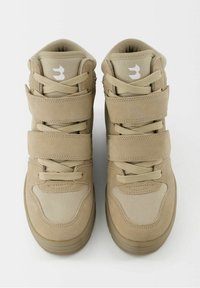 Baskets montantes beige avec panneaux en mesh et daim, maintenues par des lacets et deux larges bandes Velcro sur chaque chaussure, vues de dessus.
