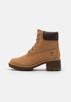 Tan leather ankle boot with brown cuff, rounded toe, metal eyelets, and laces. Features a textured sole for grip and waterproof branding.