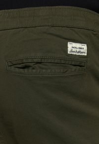 Olijfgroene shorts met een achterzak met een binnenflap en een aangehecht label met de tekst "Jack & Jones" in wit en blauw.